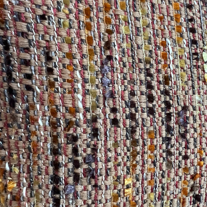 Extreme close-up detail of a rich, multi-colored tweed weave featuring interconnected threads of terracotta orange, ochre yellow, brown, and subtle purple.