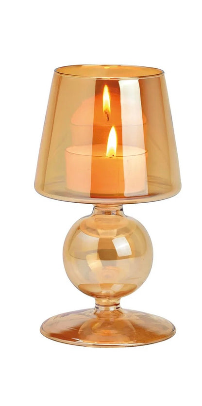 Warm amber goblet-style glass candle holders with lit candles inside, against a white background.