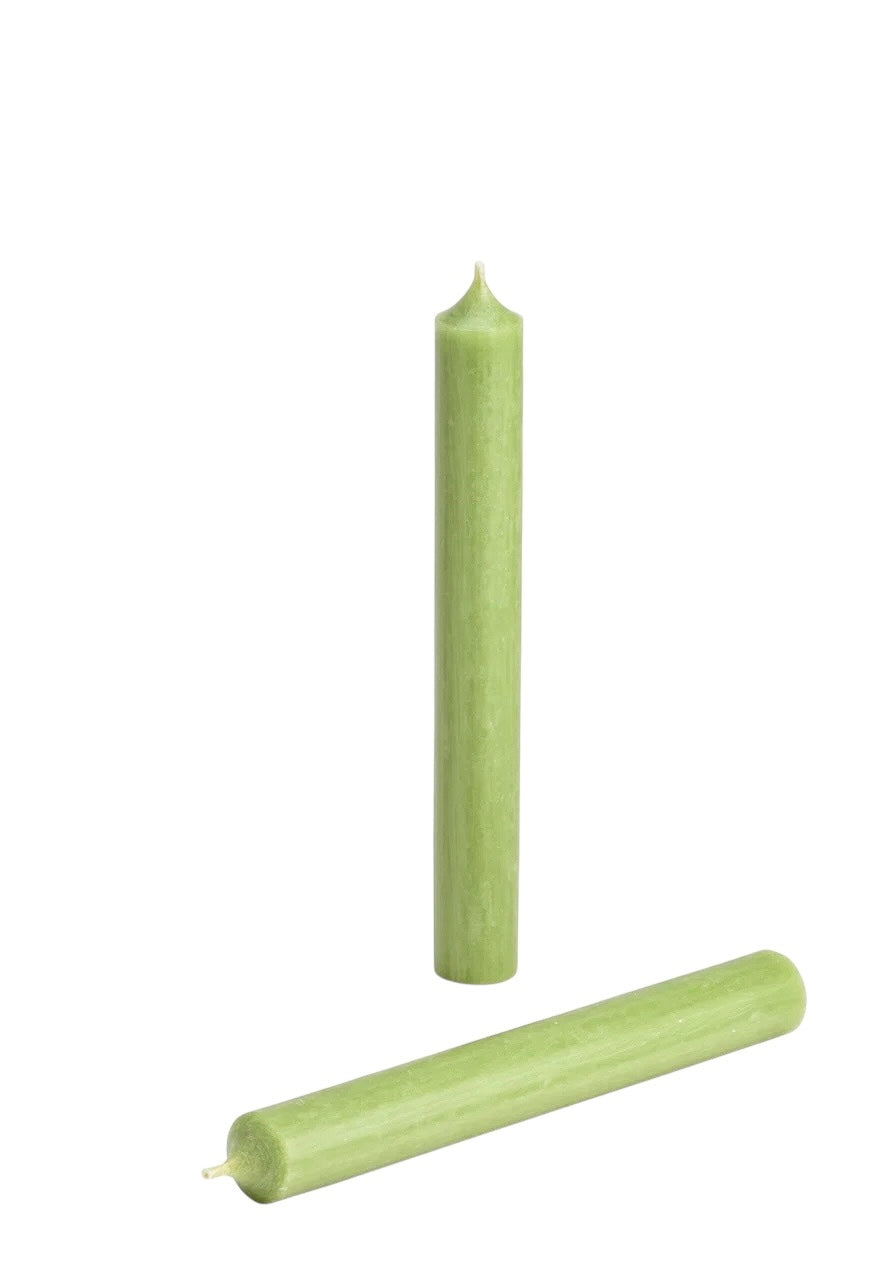 A sage green colored wax candle that is not melted, shown with a lit end facing up and a separate piece to the side.