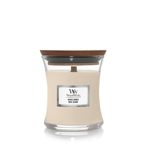 A WoodWick White Honey scented candle in a small hourglass-shaped glass jar with a dark wooden lid, featuring a white label on the front against a clean white background.