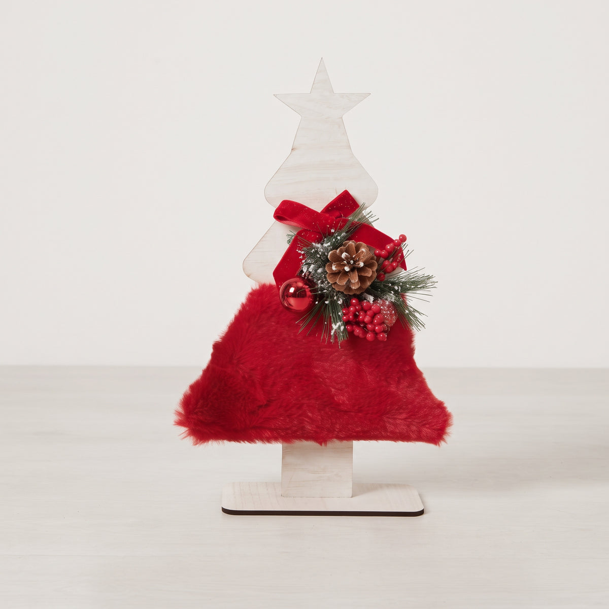 Handmade wooden star Christmas tree centerpiece decorated with pine branches, pinecones, and a red holiday ornament.