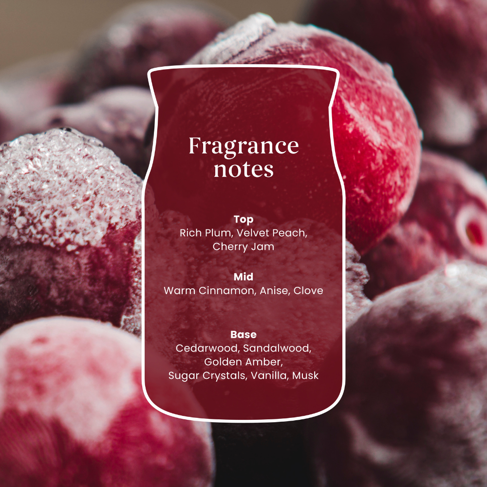 A close-up of frosted red fruits with a central label reading 'Fragrance notes' and listing scent components such as rich plum, velvet peach, cherry jam, warm cinnamon, anise, clove, cedarwood, sandalwood, golden amber, sugar crystals, vanilla, and musk.