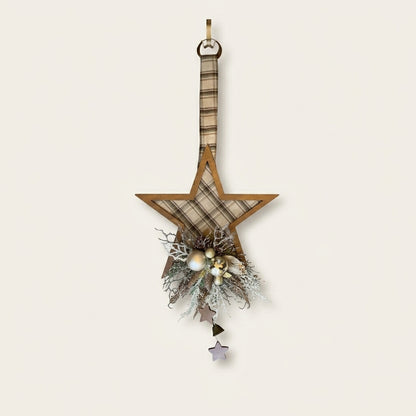 A rustic wooden star-shaped hanging ornament decorated with a beige and brown plaid fabric center, a hanging loop at the top, and a decorative cluster at the bottom featuring faux pine branches, small white berries, and dangling star charms.