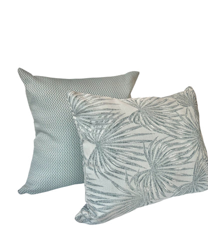 a square silver pillow with a subtle textured pattern with a tropical turquoise pillow